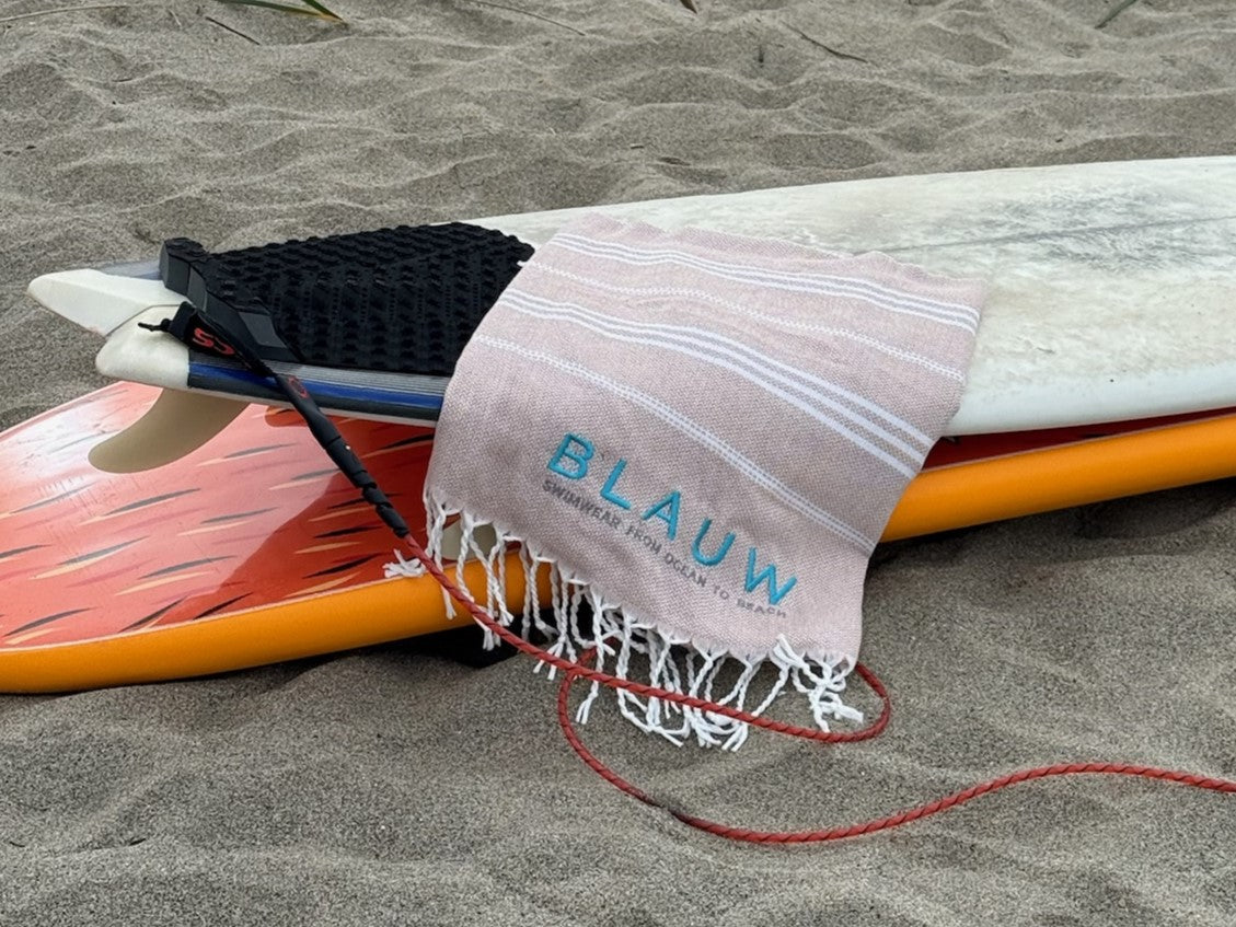 Sustainable beach towel made from recycled materials laid out on a surfboard; eco-friendly towel for surfers and recycled swimwear lovers.