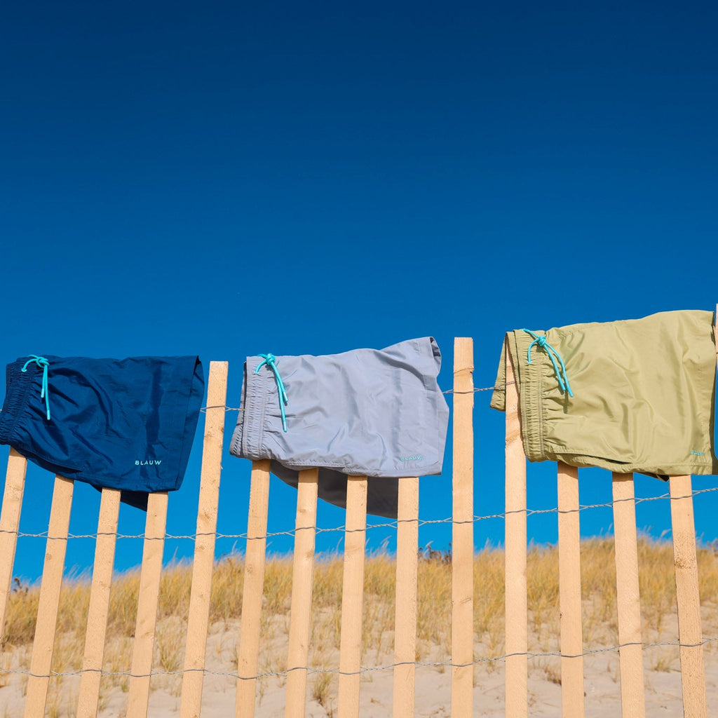 Recycled swim shorts from ocean plastic hanging on a fence.