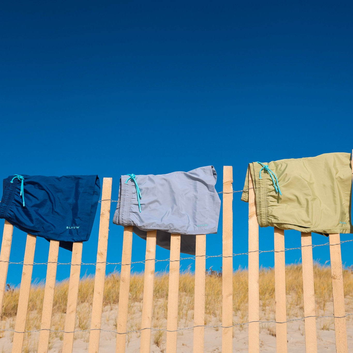 Recycled swim shorts from ocean plastic hanging on a fence.