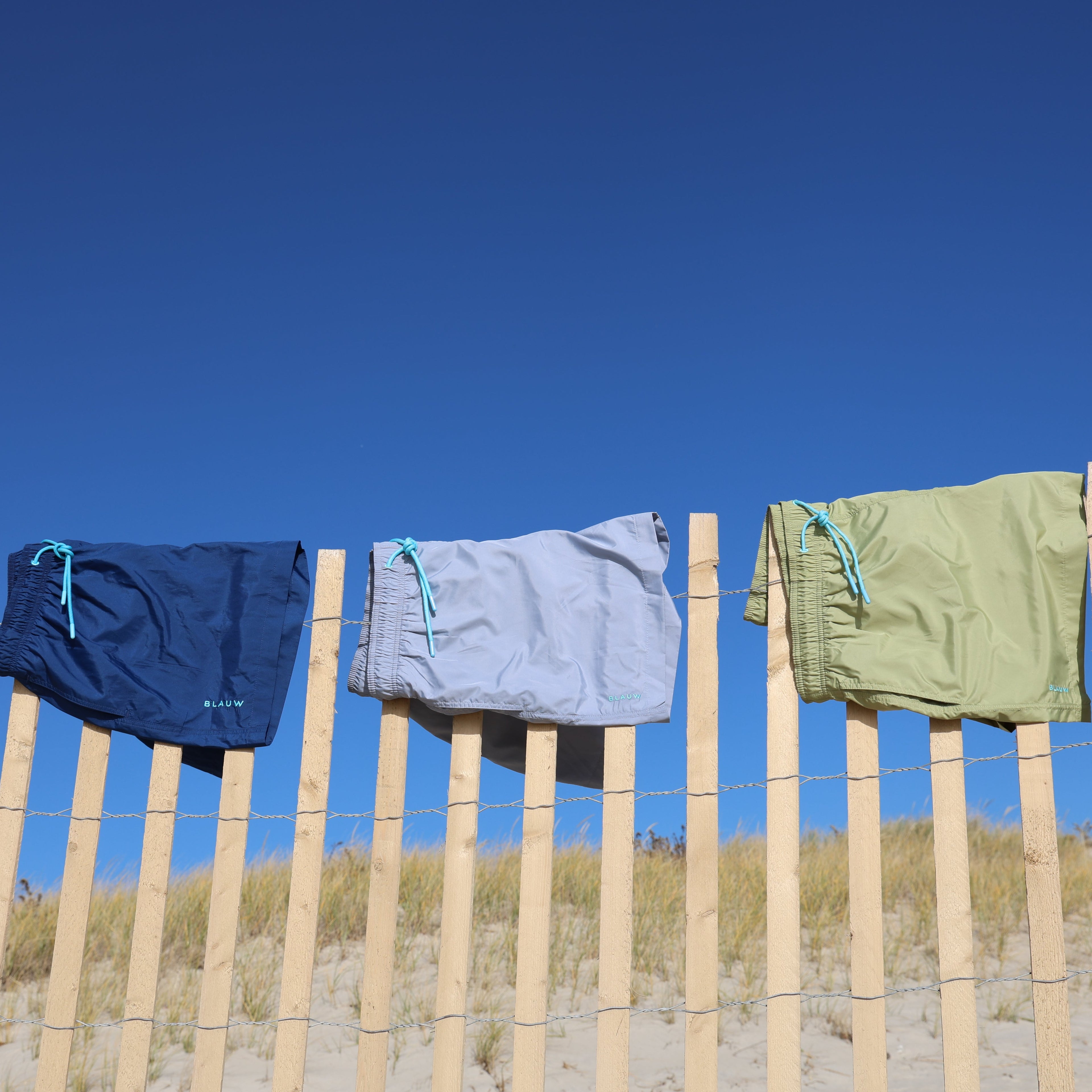 Recycled swim shorts from ocean plastic hanging on a fence.