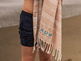 Man wearing quick dry swim shorts drying off with a sustainable beach towel