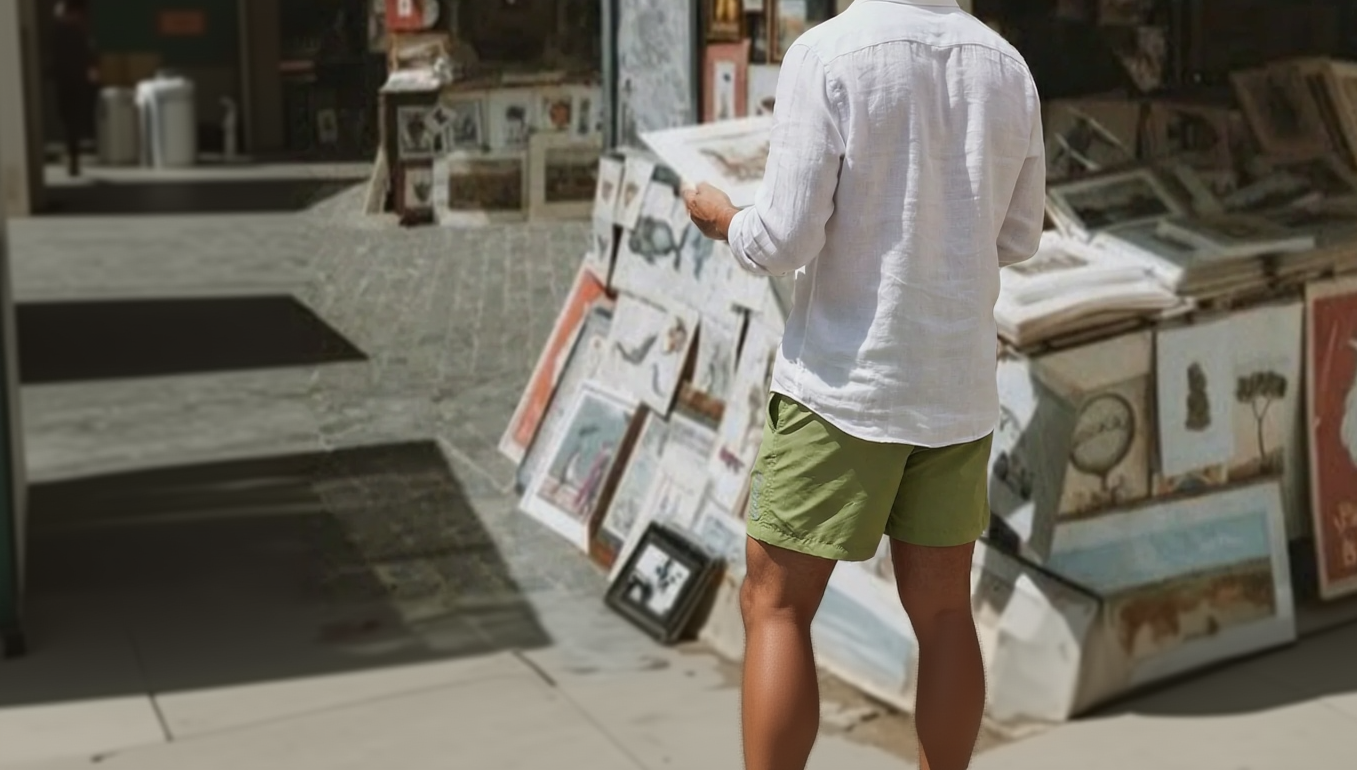 Person browsing through art prints at an outdoor market in his minimalistic swim shorts.