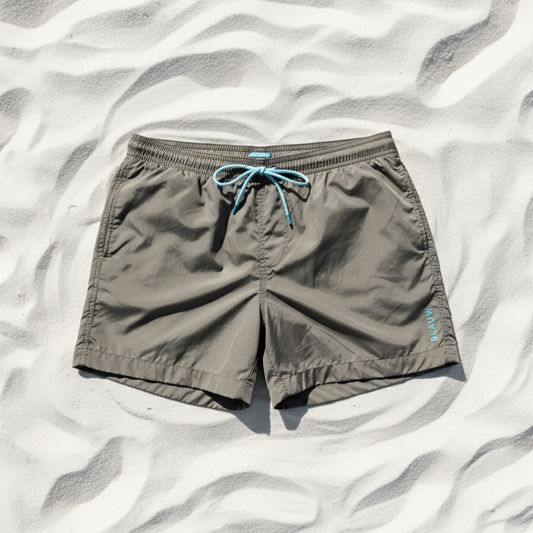 Gray swim shorts from ocean plactic with a blue drawstring on a sandy background